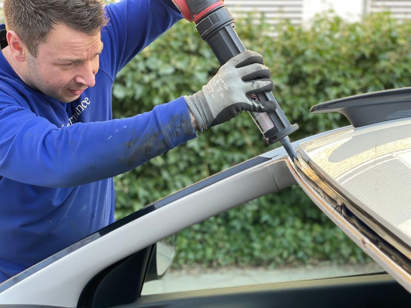 A1 Autoglass technician applying sealant while fitting a windscreen on site
